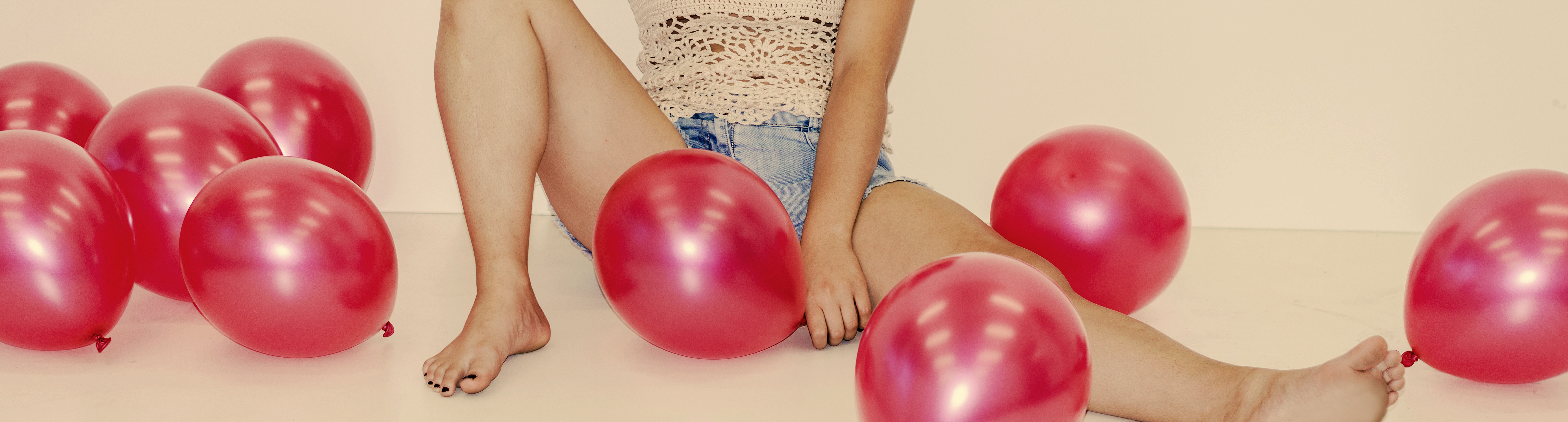 eine Frau sitzt auf dem Fußboden, umgeben von vielen roten Luftballons