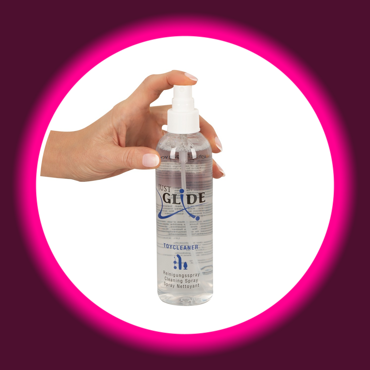 Just Glide Toycleaner Reinigungsspray für Sextoys in transparenter Flasche mit weißem Sprühkopf, Frontansicht mit einer Hand am Sprühkopf