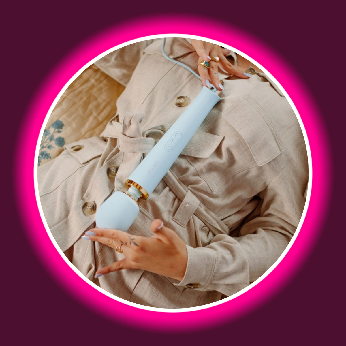 le WAND Powerful Plug-In Massagestab in Hellblau – in den Händen einer Frau im beigen Trenchcoat liegend gehalten, Schrägansicht mit Goldring-Detail und samtweichem Massagekopf