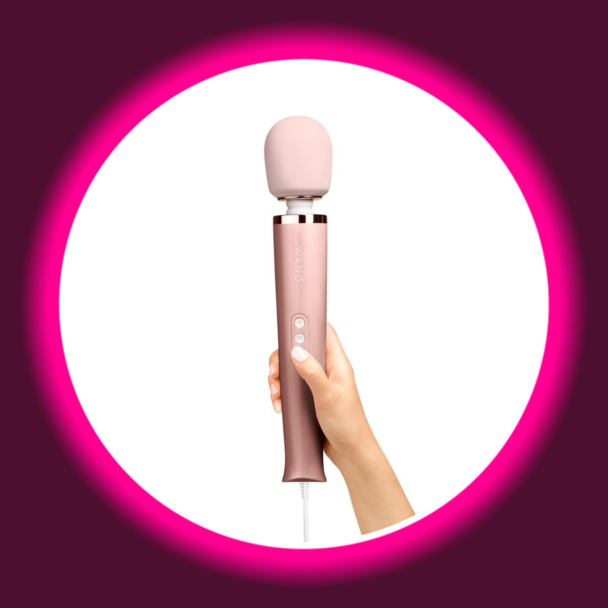 le WAND Powerful Plug-In Massagestab in der Hand gehalten – Größenvergleich, rosa Griff mit le WAND Schriftzug, samtweicher Massagekopf und 3-Button-Steuerung, weißes Netzkabel