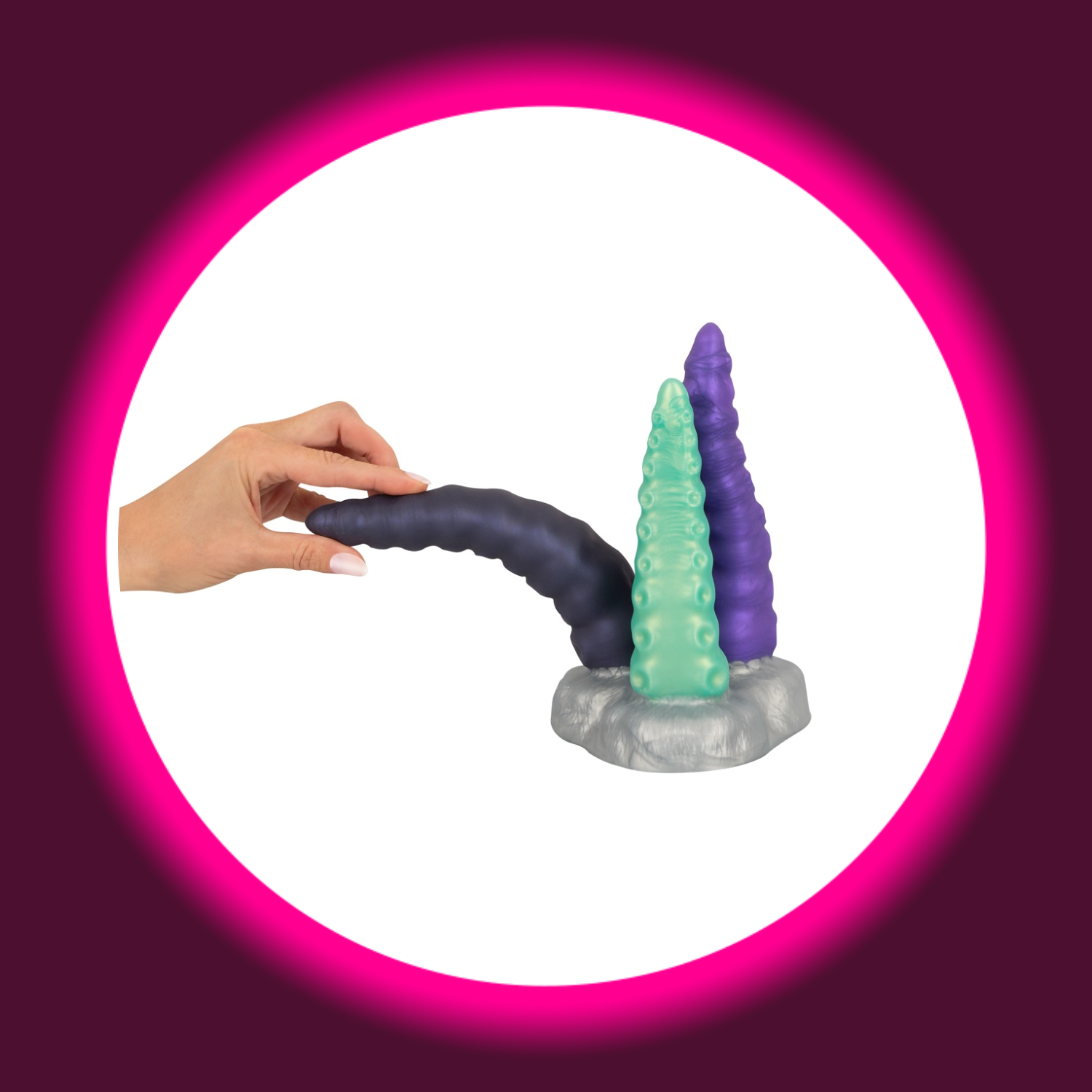 silberner Sockel mit drei Tentakel-Dildos in grün, violett und schwarz, an dem eine Hand zieht, Beasty Cocks Triple Tentacle