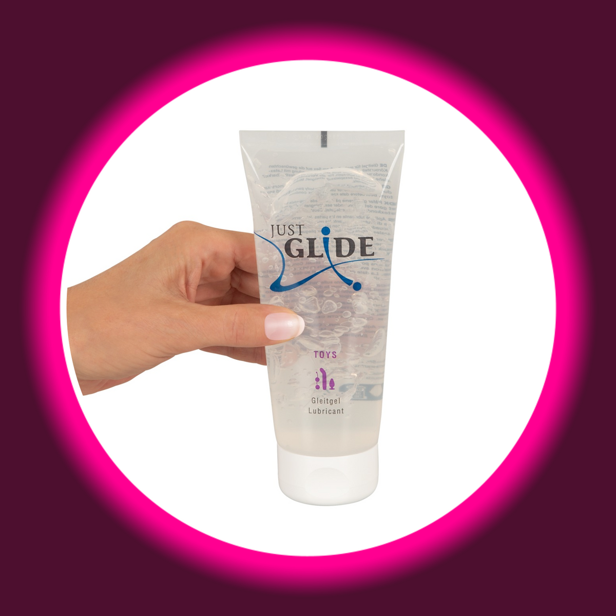 Just Glide Toys Gleitgel in der transparenten 200-ml-Tube mit weißem Verschluss und violettem Toy-Motiv, Frontansicht in einer Hand gehalten