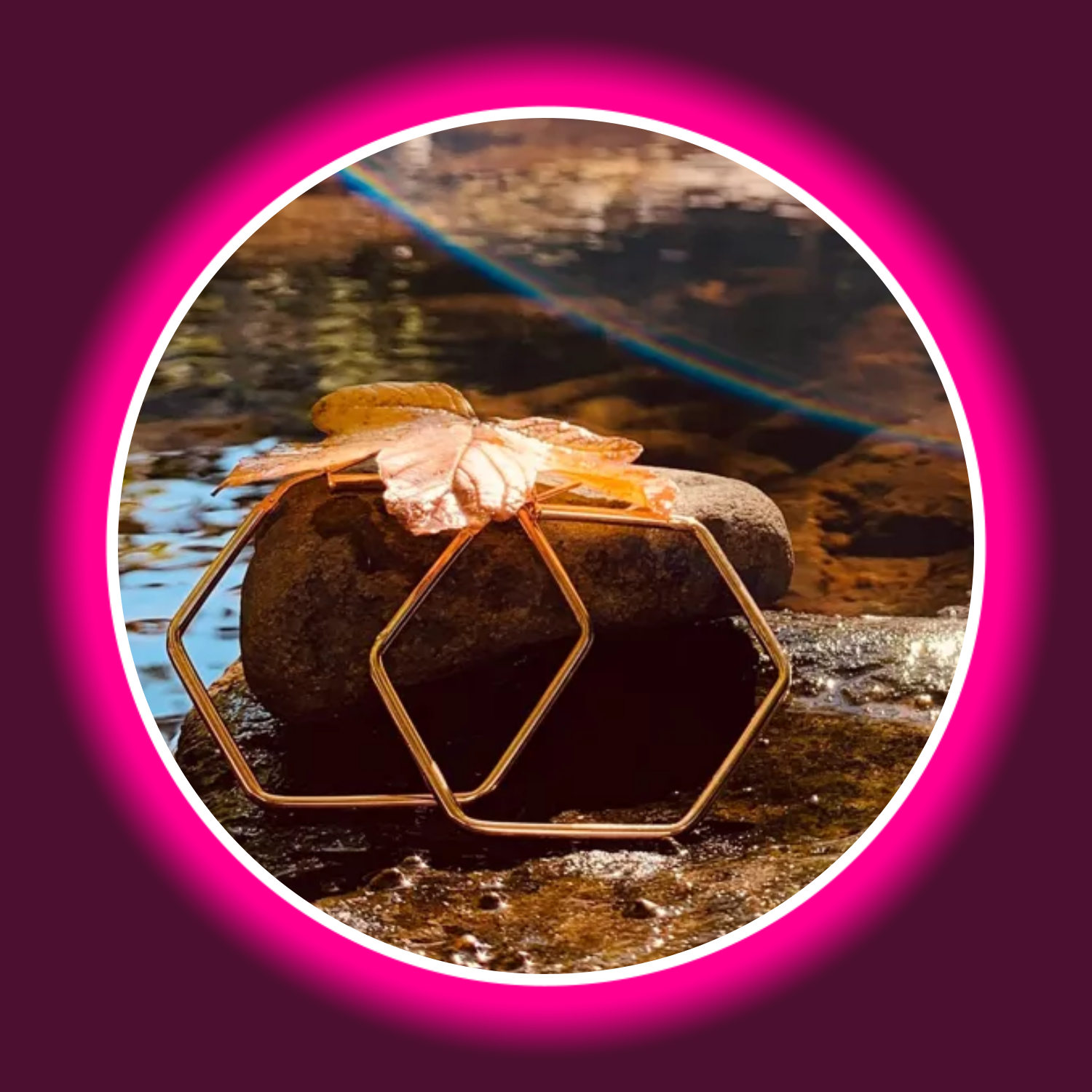 zwei rosé farbene Creolen von Modabilé an einen Stein gelehnt, darüber ein gelbes Blatt, im Hintergrund ein Bach