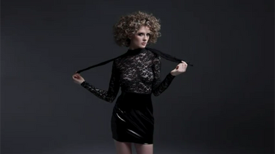 Frau in schwarzem Minikleid tanzt vor schwarzem Hintergrund - BLACK LEVEL